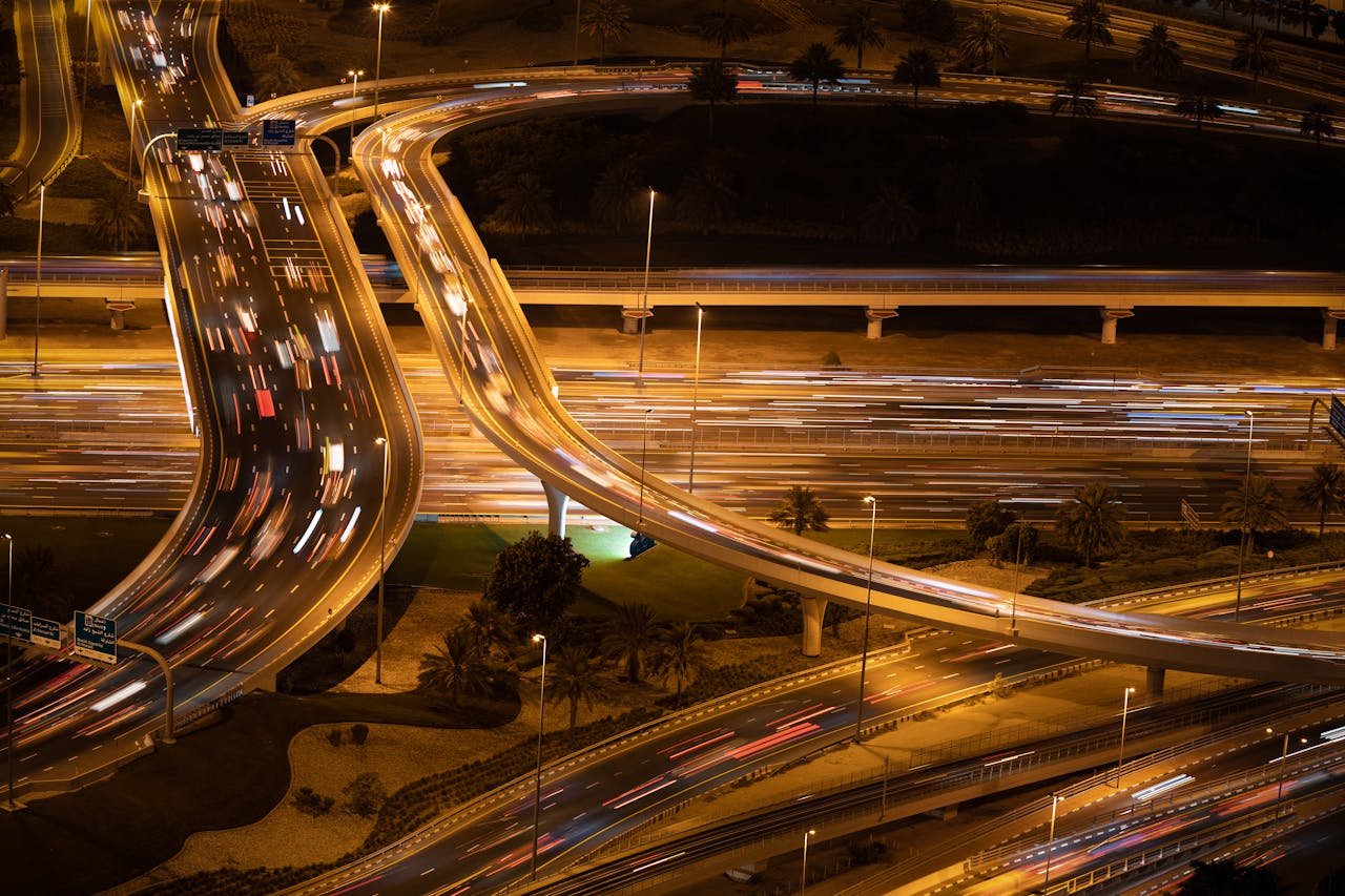 Dynamic aerial night view of a city with illuminated highway interchange and skyscrapers.